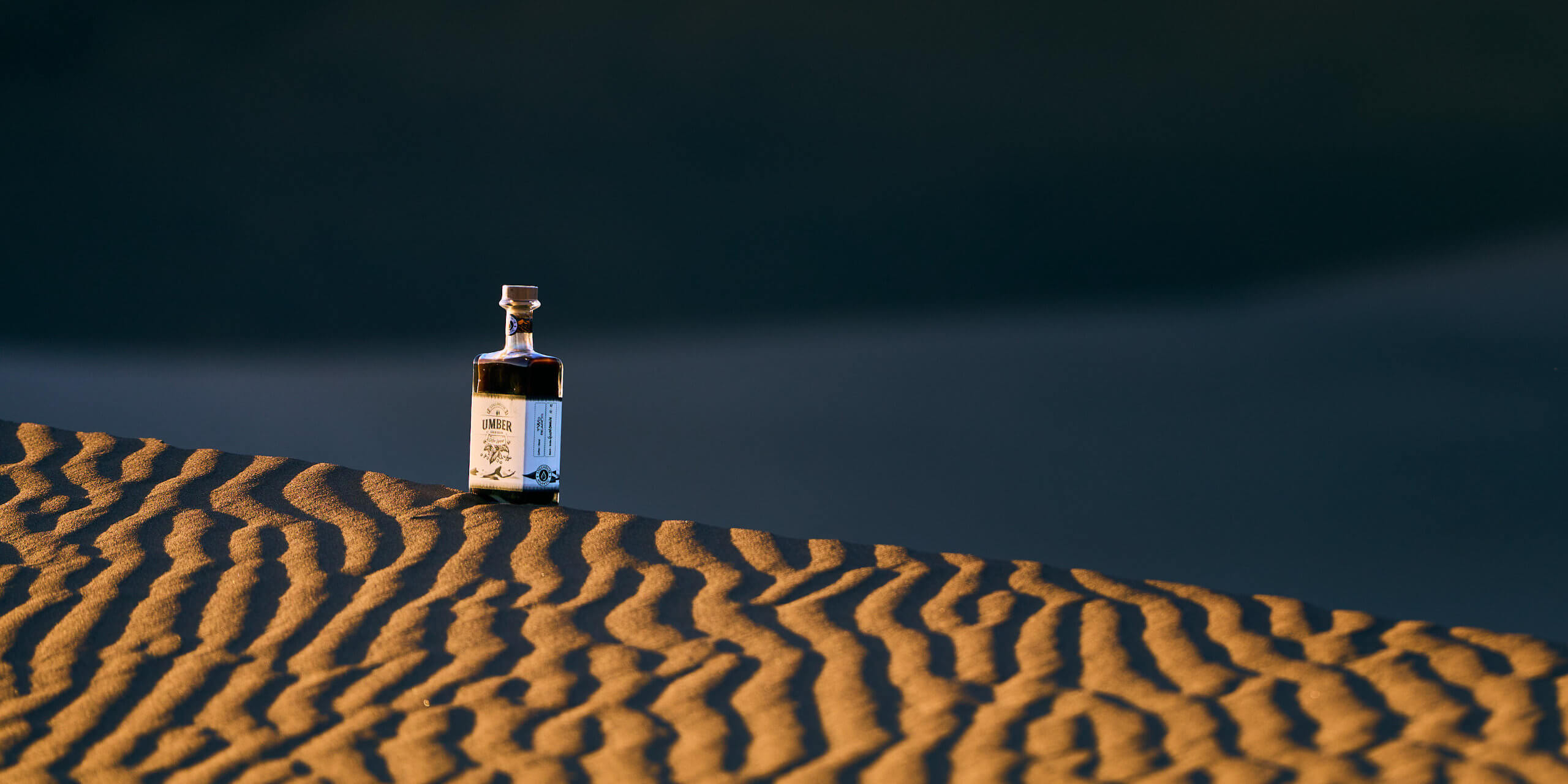 A bottle of coffee liqueur in the last light on top of a dune in the Namib.